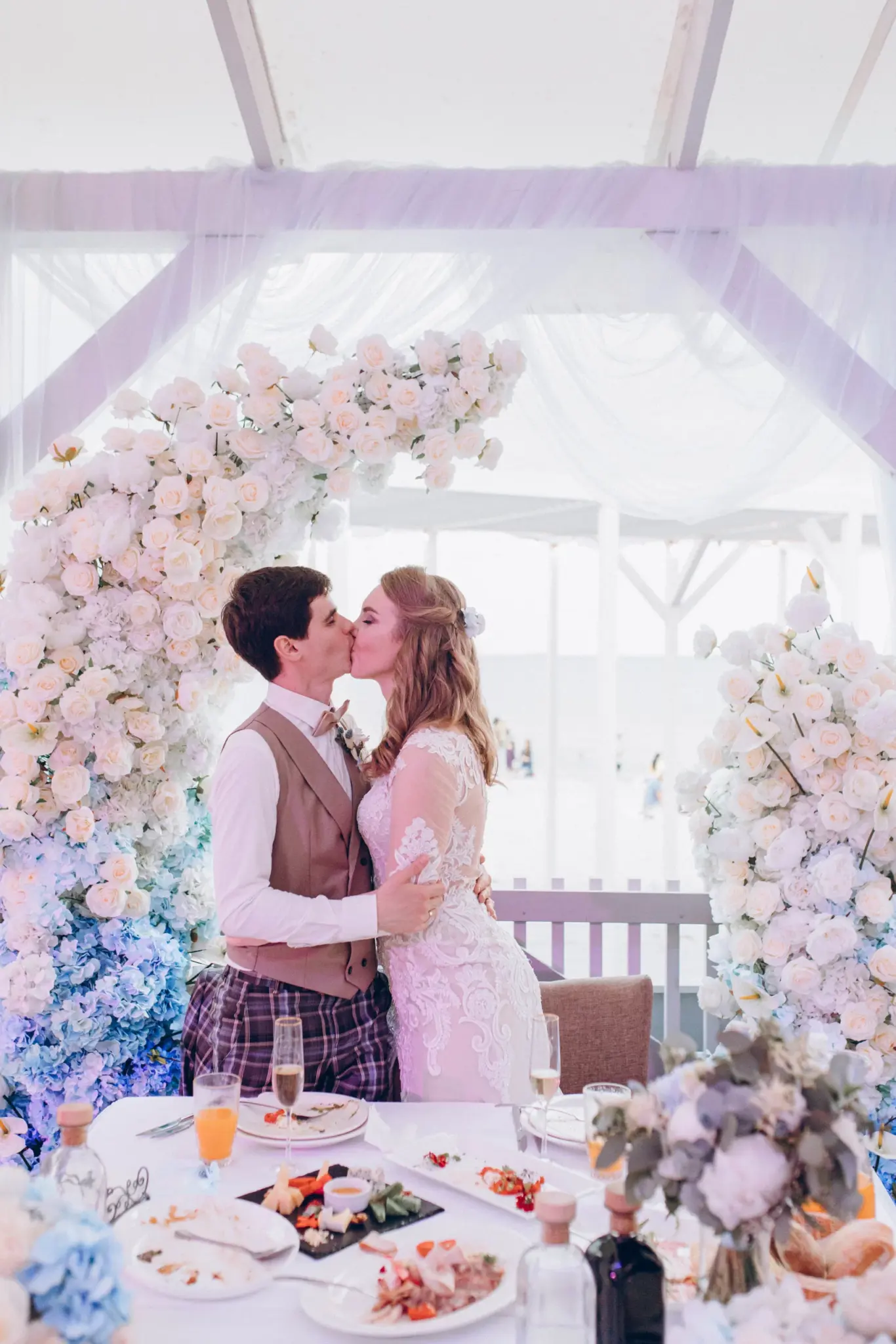 Bride and groom kissing under a flower arch