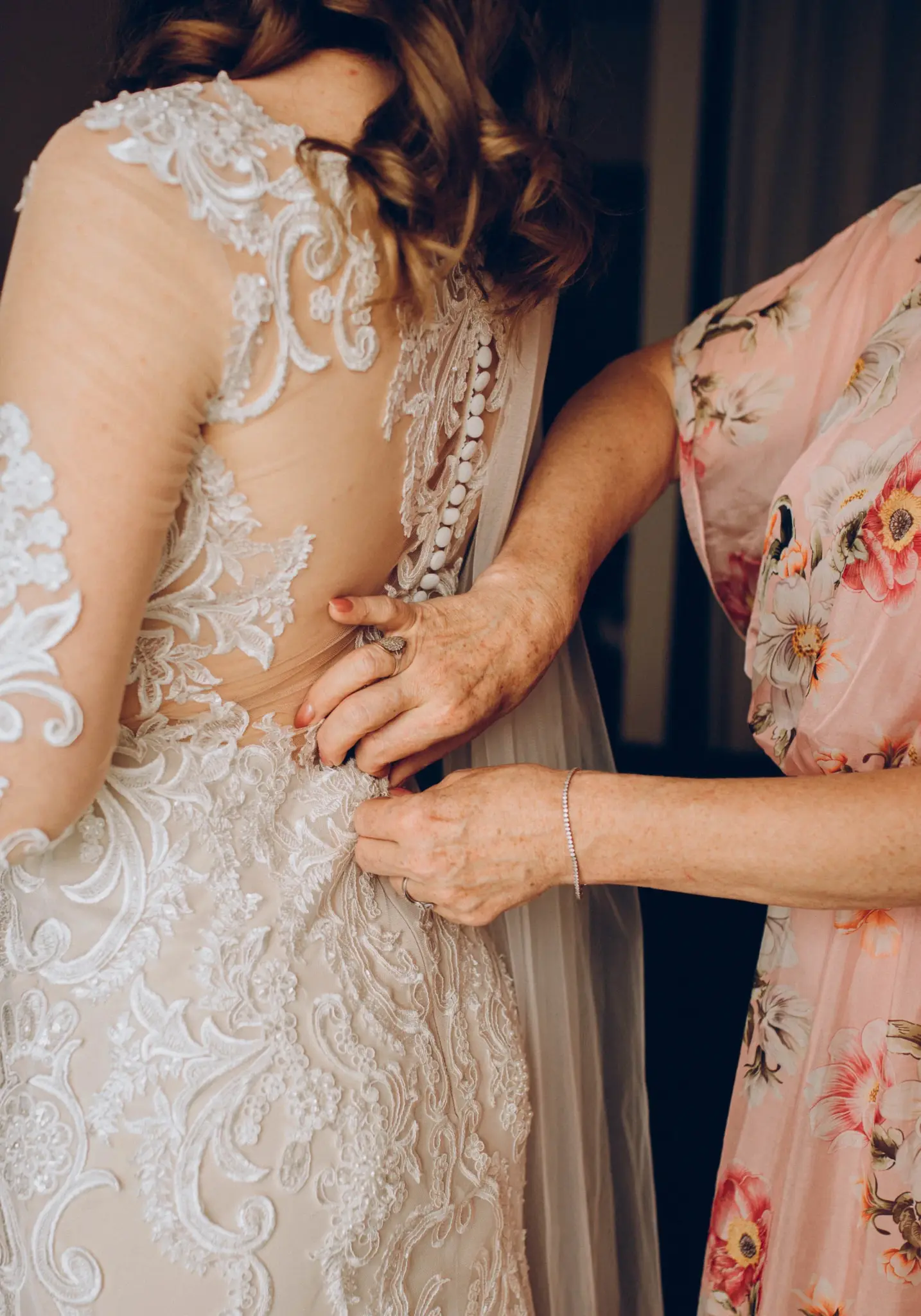Buttoning the lace back of the wedding dress
