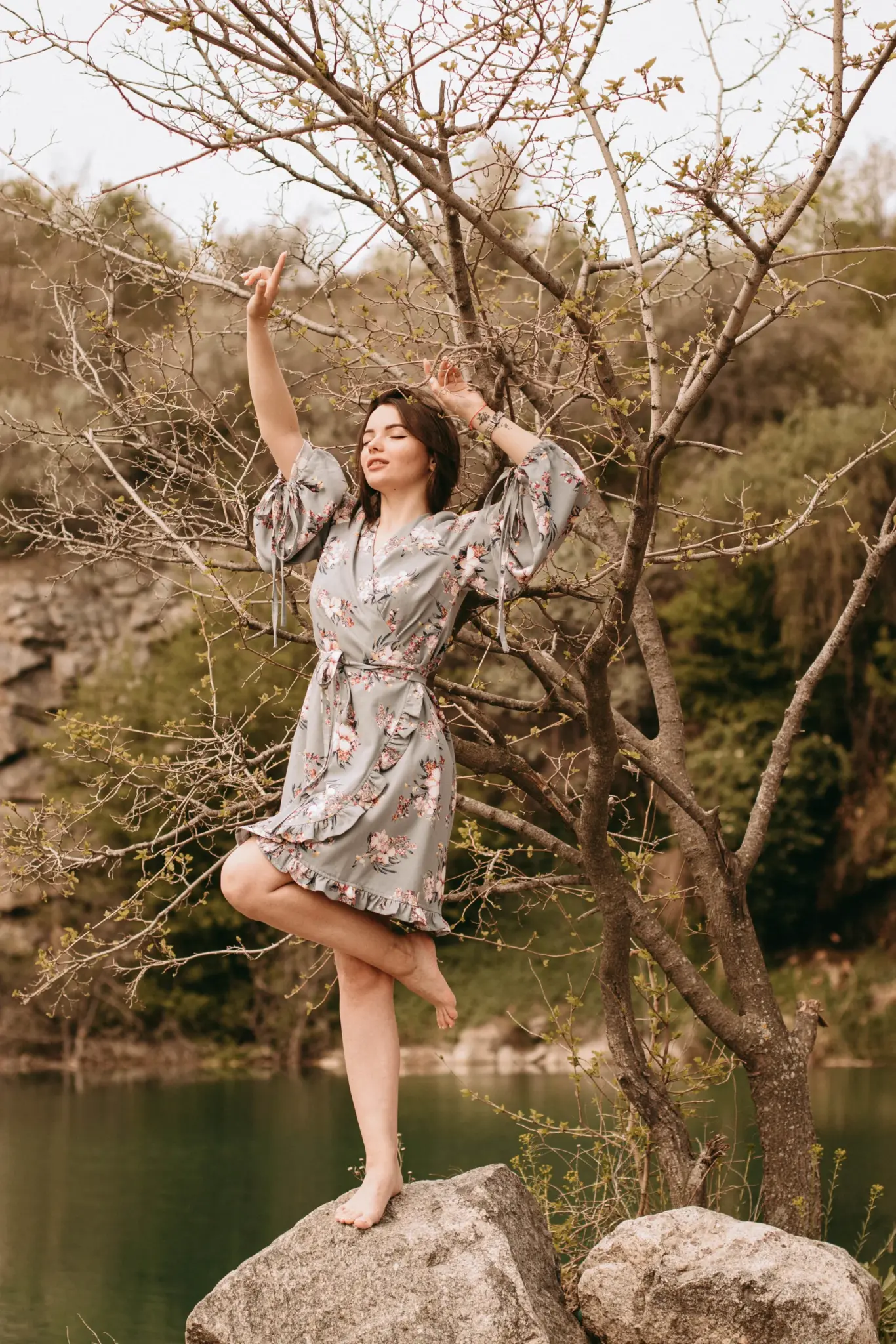 Christina in a floral dress on a rock among spring trees