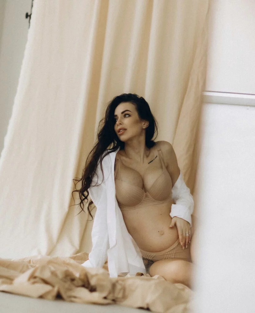 Mom-to-be at a studio pregnancy photoshoot in Paris in warm beige light