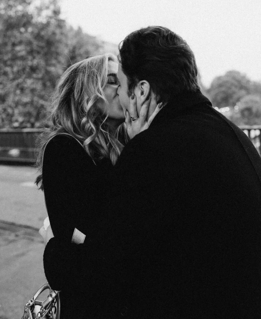 Couple share a passionate kiss as the woman cradles her partner's face, engagement ring visible - proposal