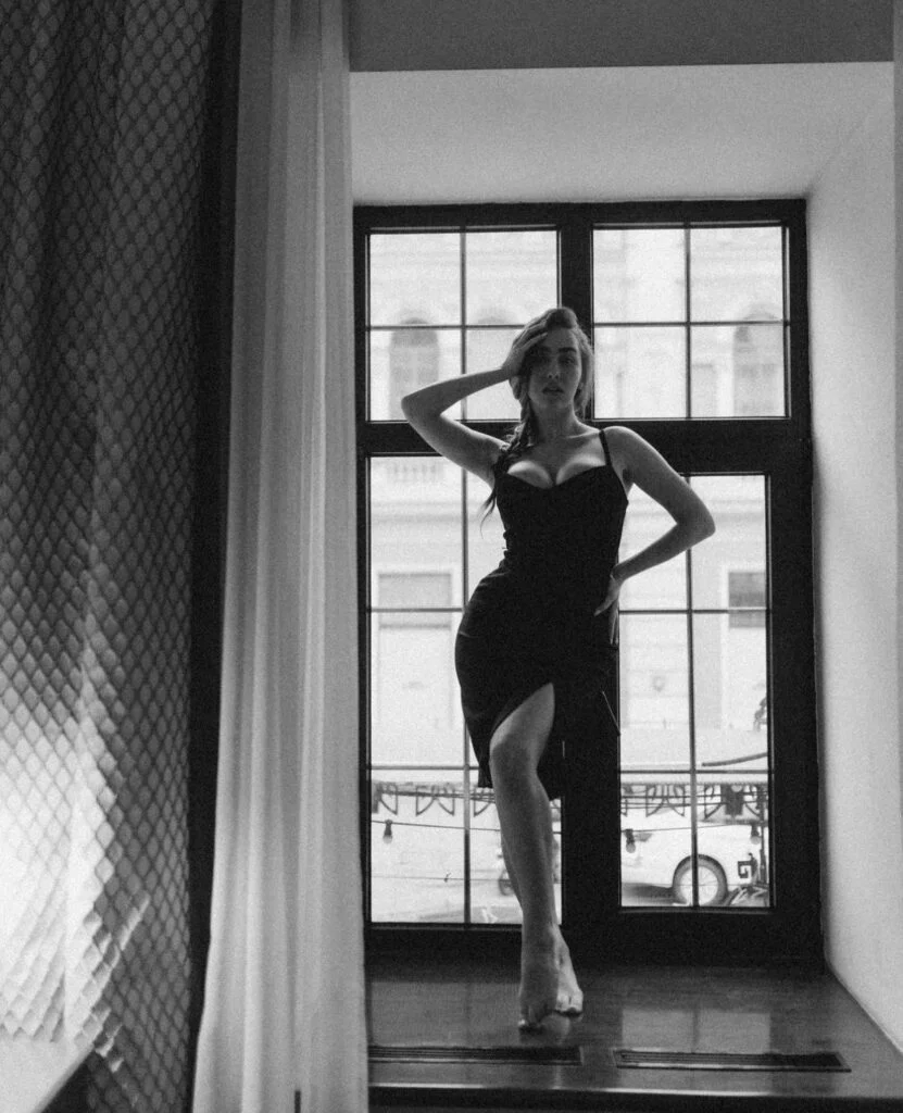 Boudoir photographer Paris session by a grand Parisian window, black and white portrait in a black dress by Julia Litvin