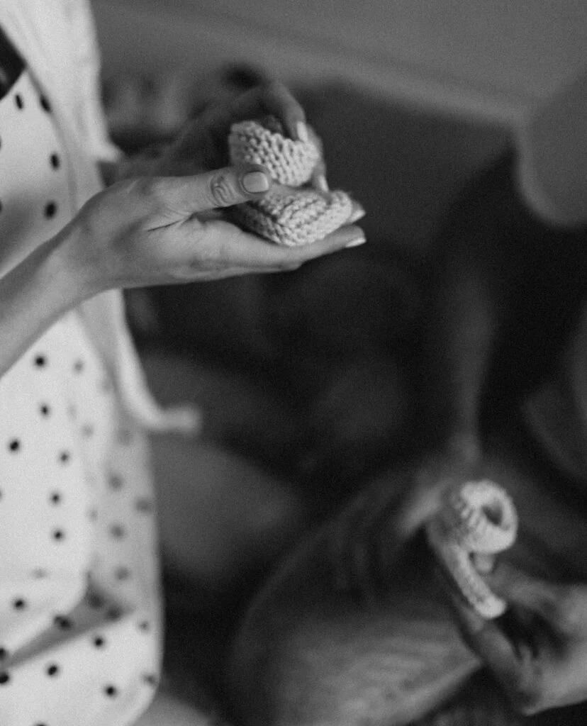 Mom-to-be holding tiny baby booties at a black and white maternity photoshoot in Paris