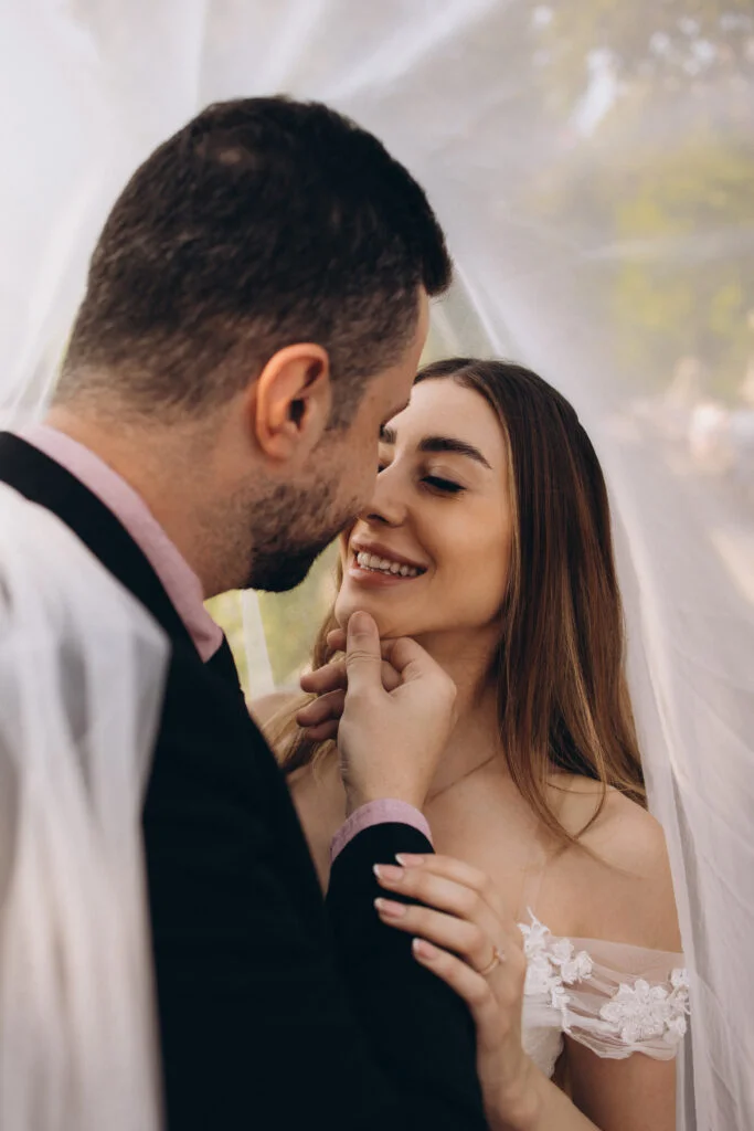Groom holding the bride close under her veil during a pre-wedding photoshoot in Paris