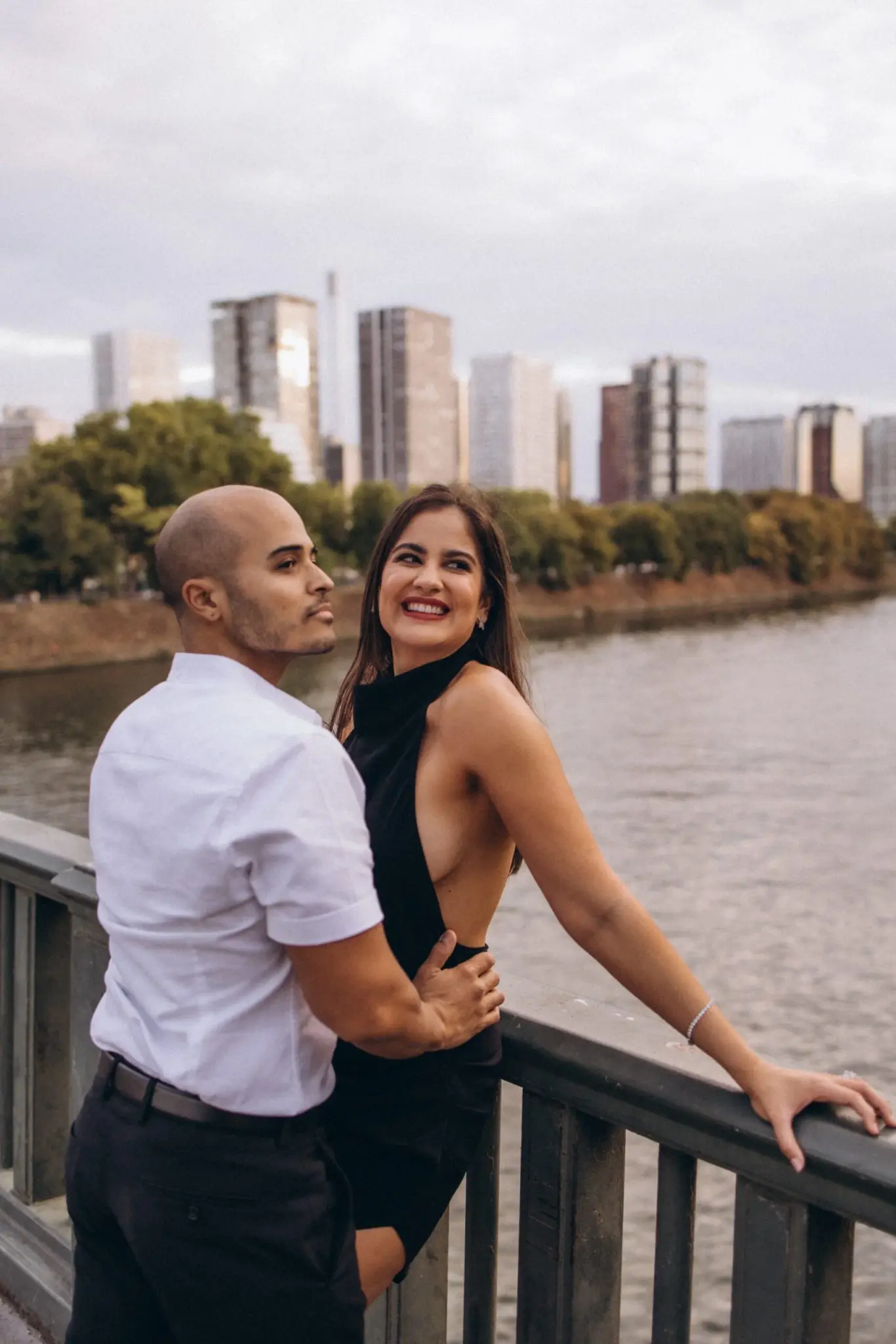 Elegant couple leaning on a railing by the Seine with the Paris skyline behind