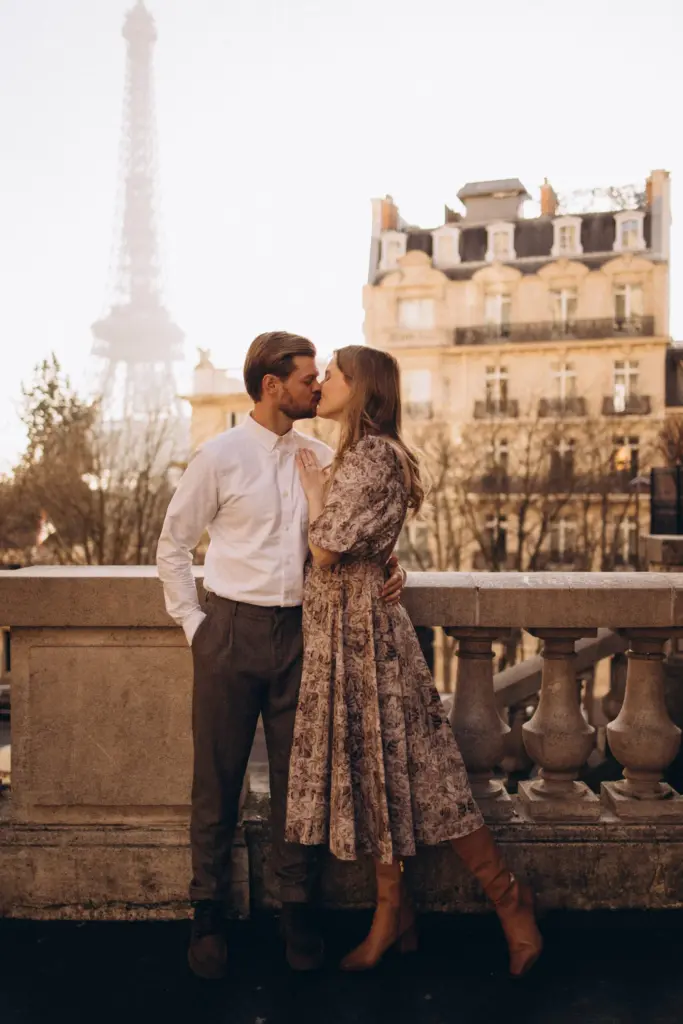 Newlywed couple kissing during a Paris honeymoon photoshoot with the Eiffel Tower in soft golden light