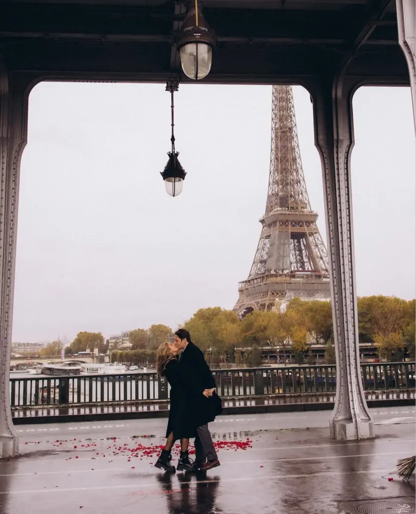 Couple kissing under the lantern on Pont de Bir-Hakeim in the rain, photographed by couples photographer Julia Litvin in Paris