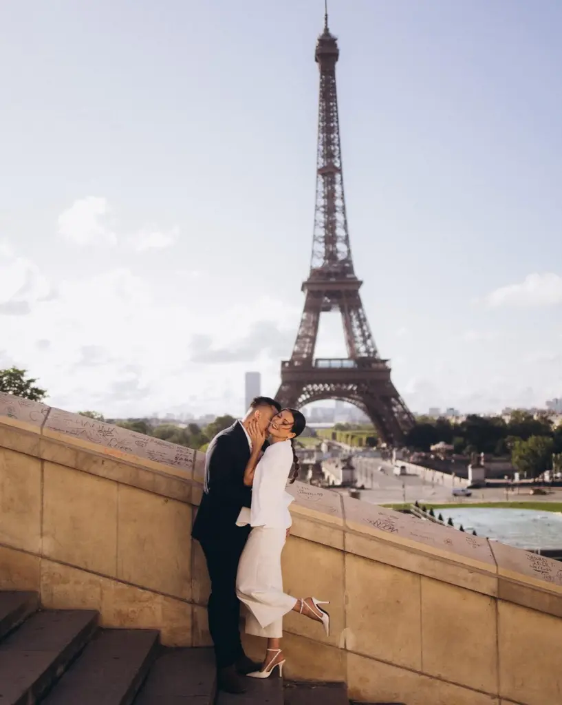 Romantic photoshoot for couples on the Trocadéro terrace in Paris, a couple in white and black by the stone balustrade, by Julia Litvin