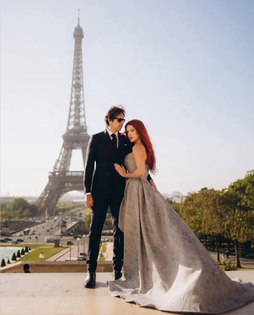 Paris couple photoshoot on the Trocadéro terrace, a woman in a silver gown with a long train and a man in a black suit, by Julia Litvin