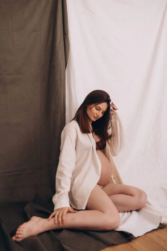 Expecting mother at a pregnancy photoshoot in Paris against minimalist drapery