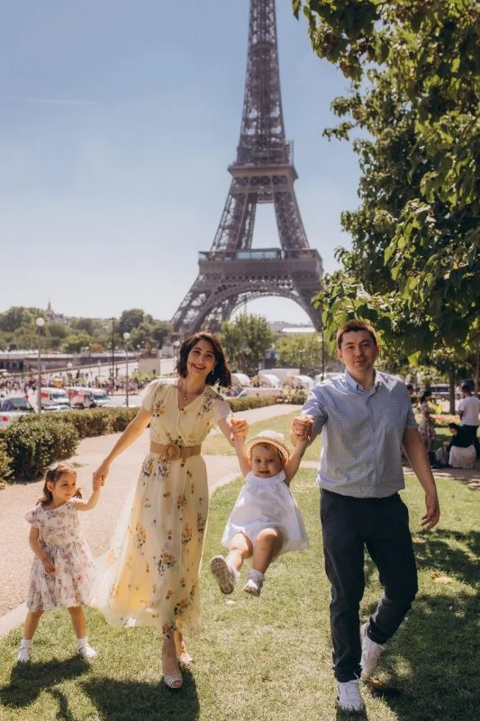 Family walking hand in hand on the lawn by the Eiffel Tower