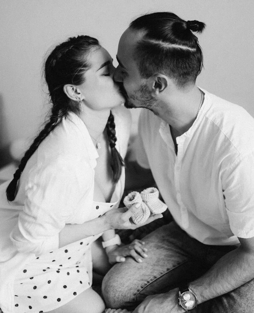 Parents-to-be holding baby booties at a black and white maternity photoshoot in Paris