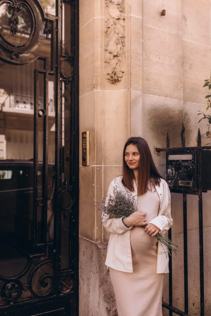 Mom-to-be with lavender at a maternity photoshoot in Paris by a wrought iron gate