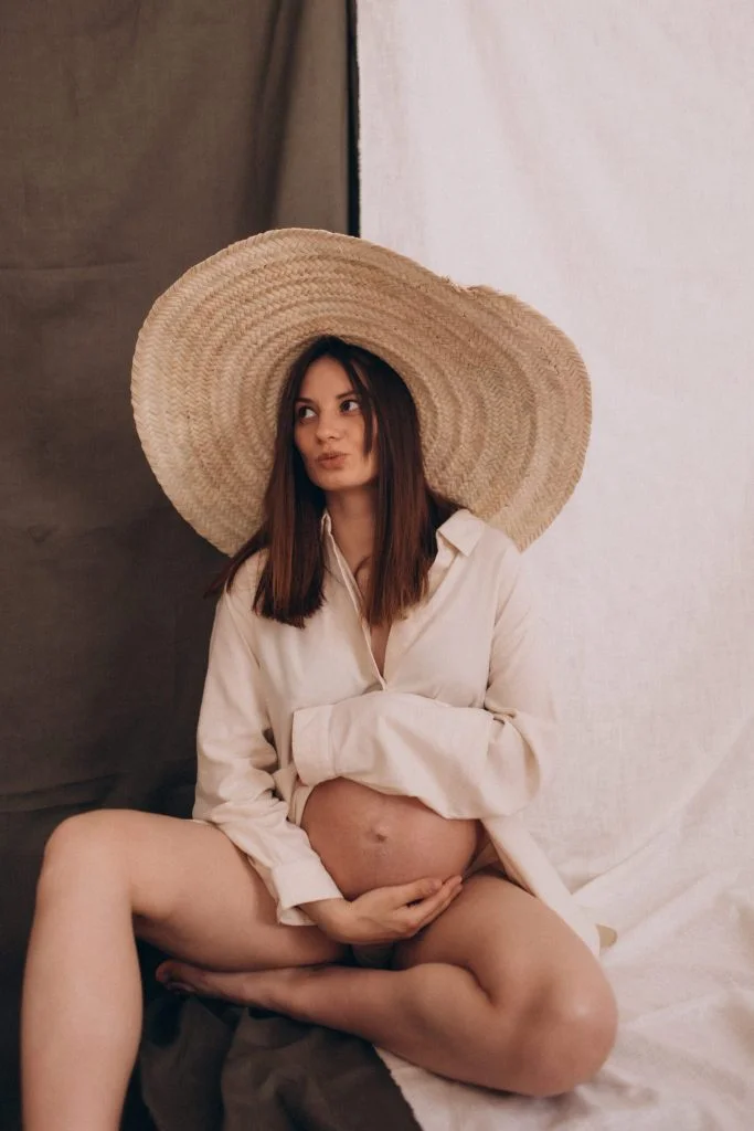Mom-to-be in a straw hat at a pregnancy photoshoot in Paris cradling her bump