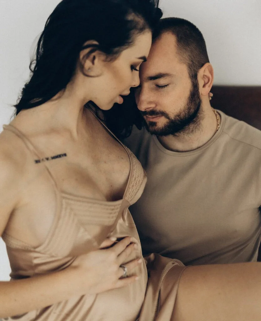 Parents-to-be forehead to forehead at a maternity photoshoot in Paris in warm light