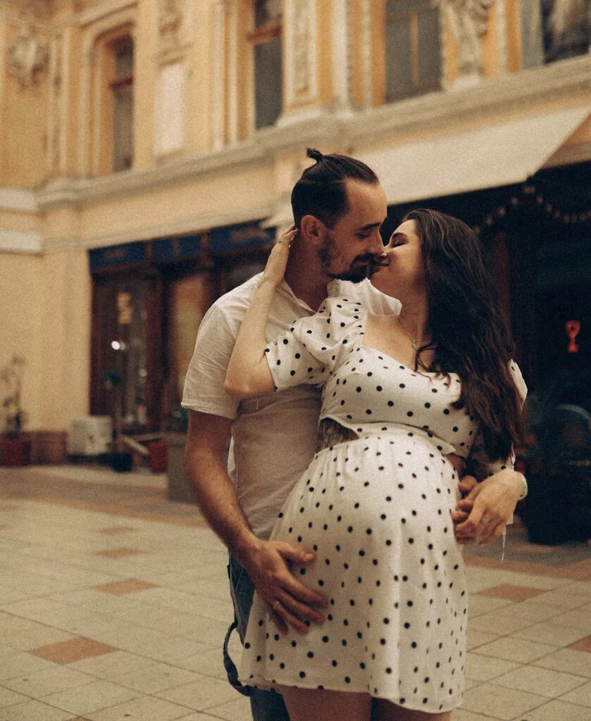 Expecting couple kissing in a historic Parisian passage at a maternity photoshoot in Paris