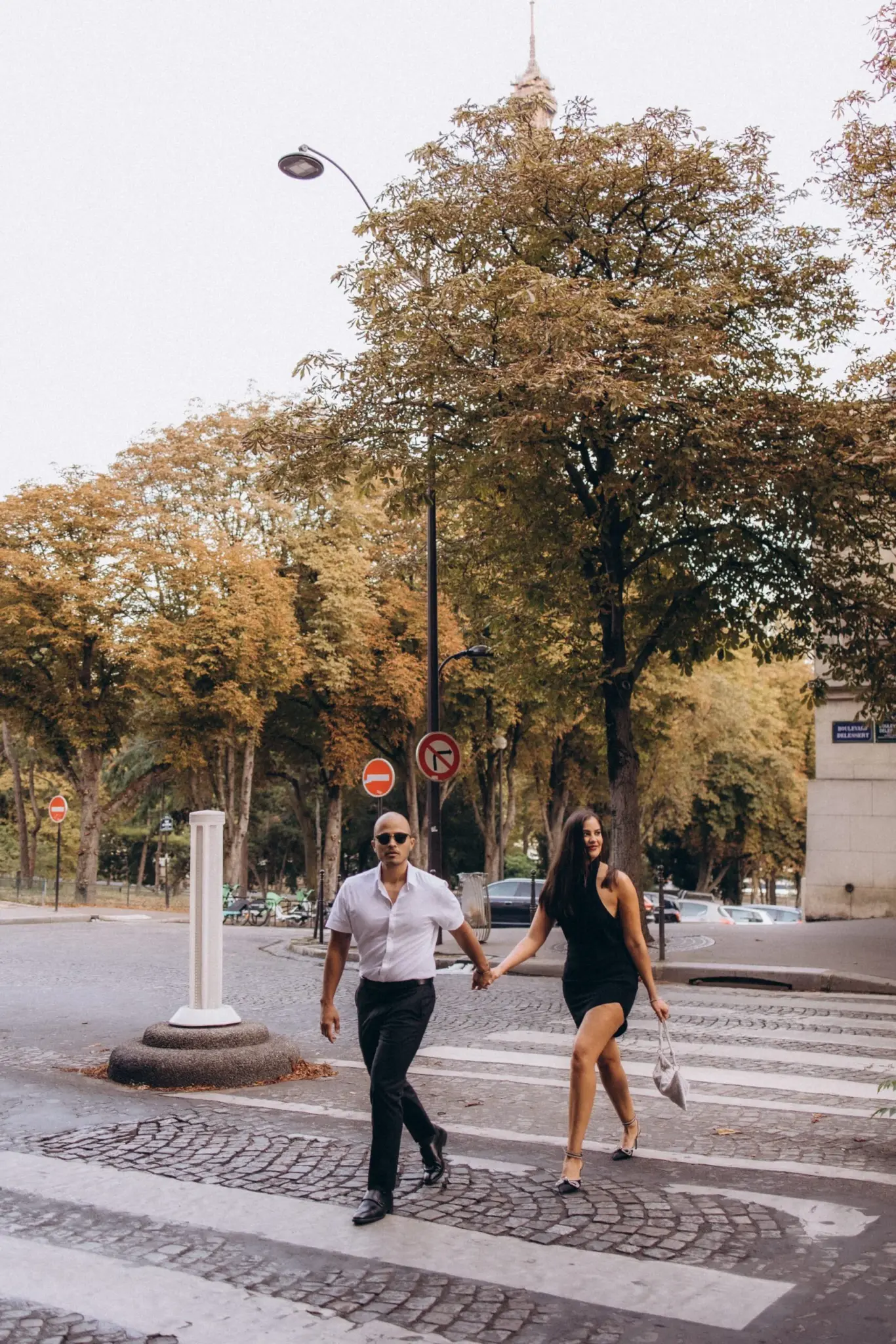 Couple crossing a tree-lined Paris street hand in hand
