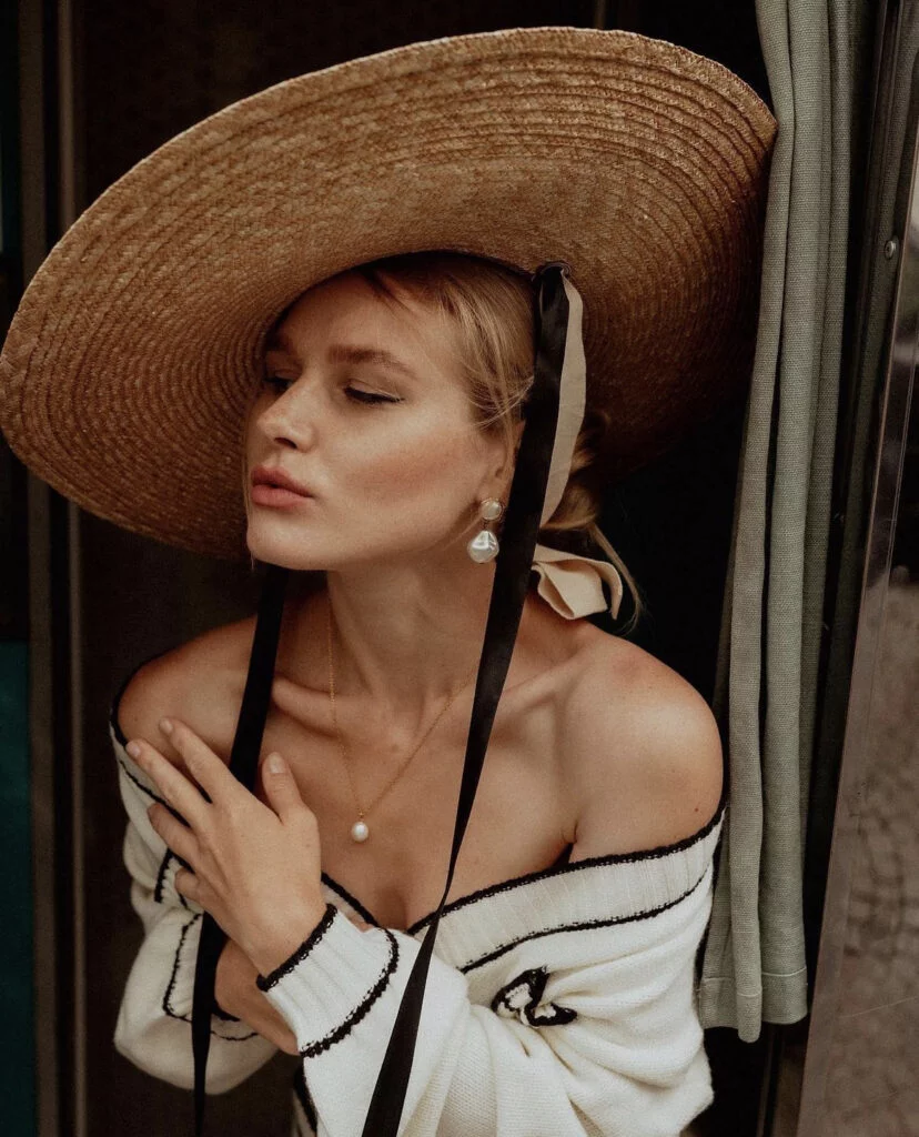 Close-up portrait photography in Paris, a woman in a wide-brimmed straw hat with pearl earrings