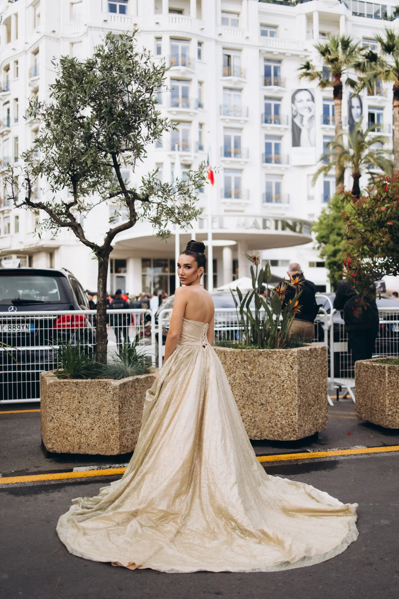 Woman in a champagne gown with a long train on a Cannes street lined with palace hotels