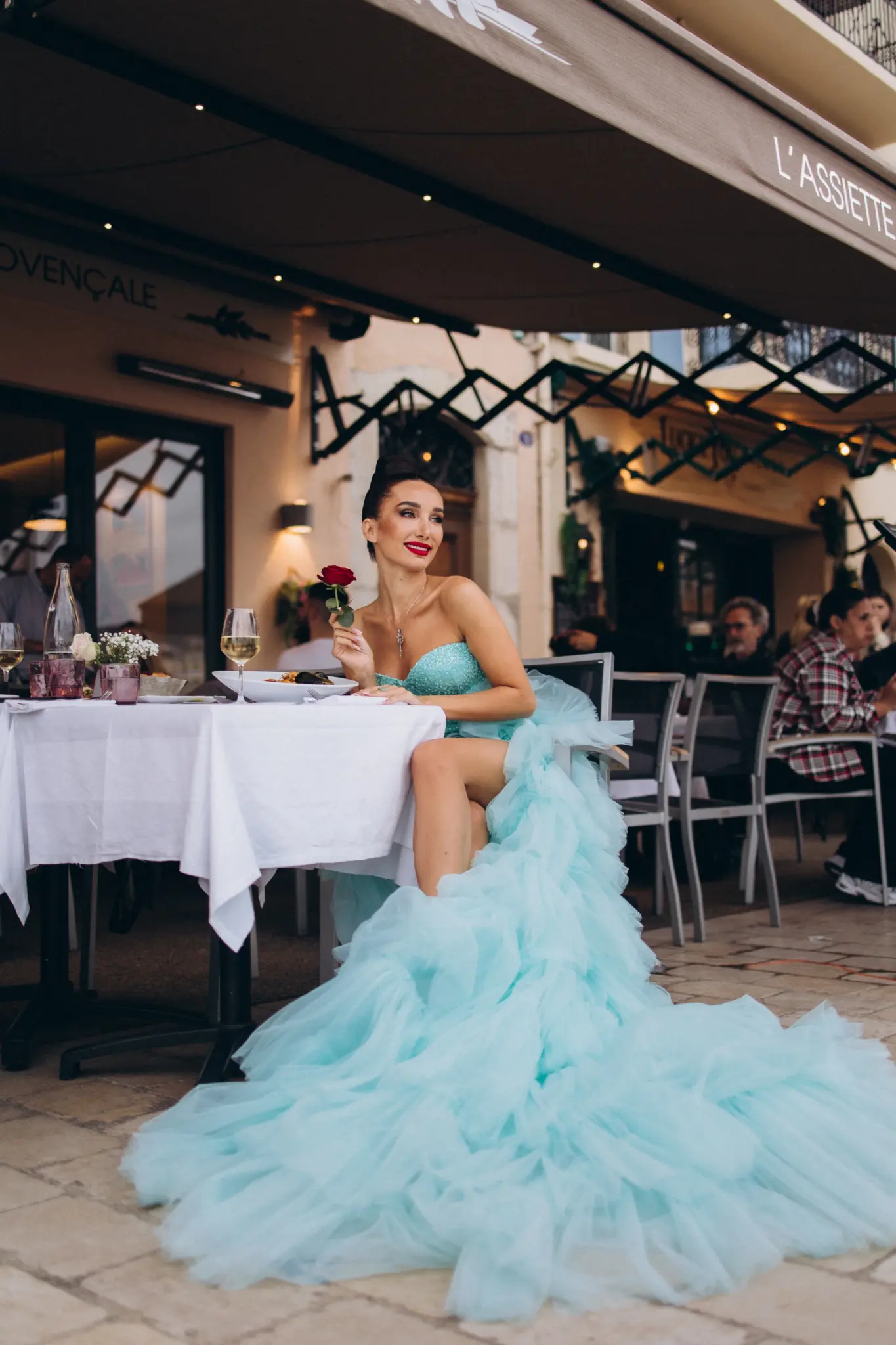 Woman in an aqua tulle gown on a restaurant terrace in Cannes