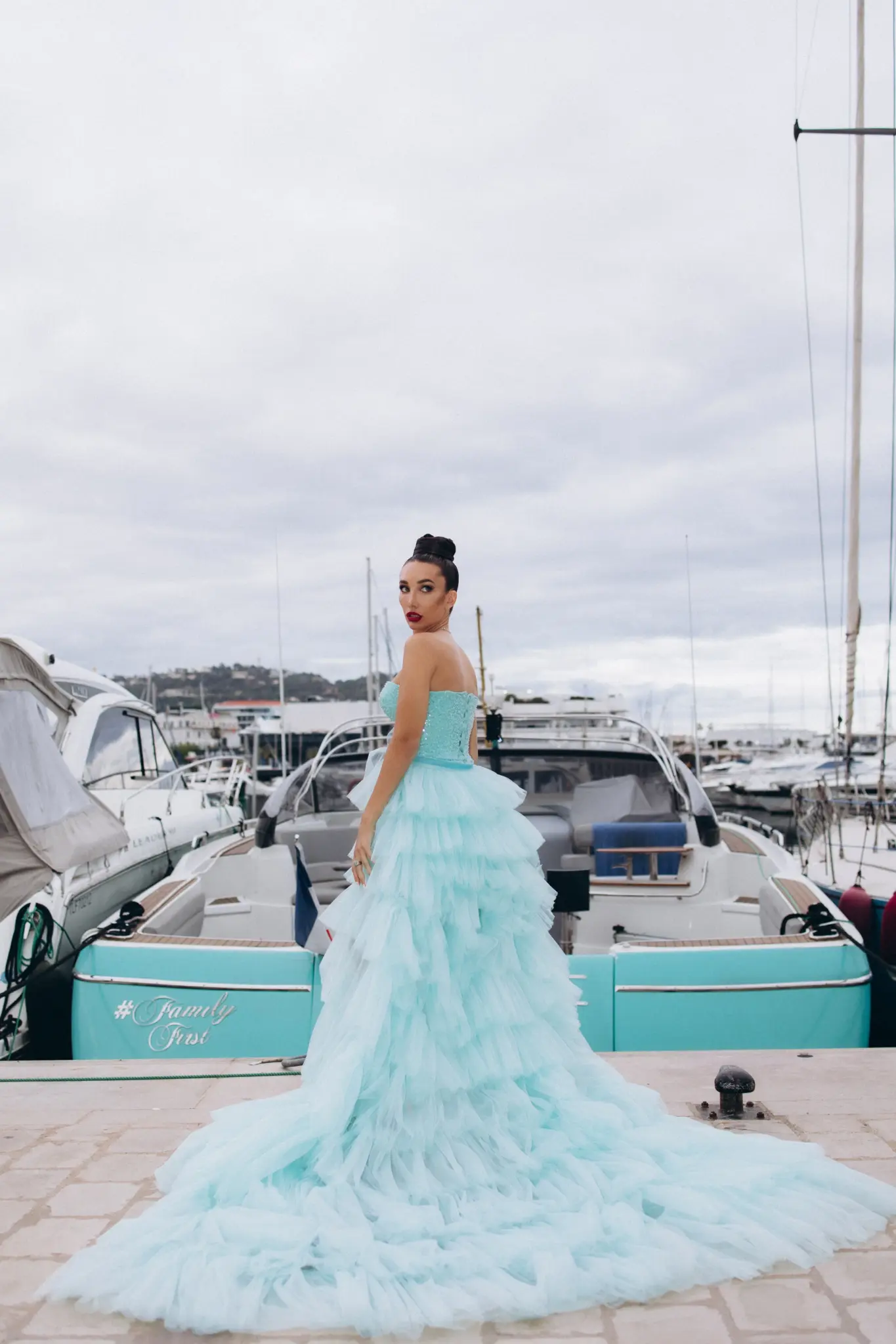 Woman in an aqua tulle gown on the deck of a yacht in the port of Cannes