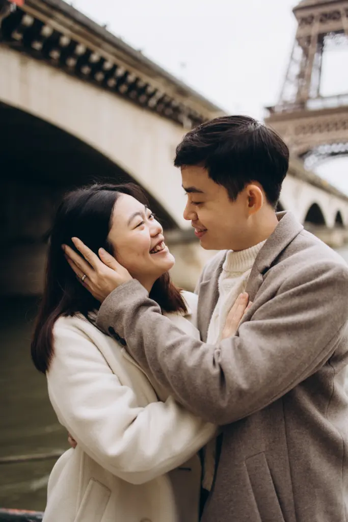 Couple embracing under the arches of Pont d’Iéna with the Eiffel Tower
