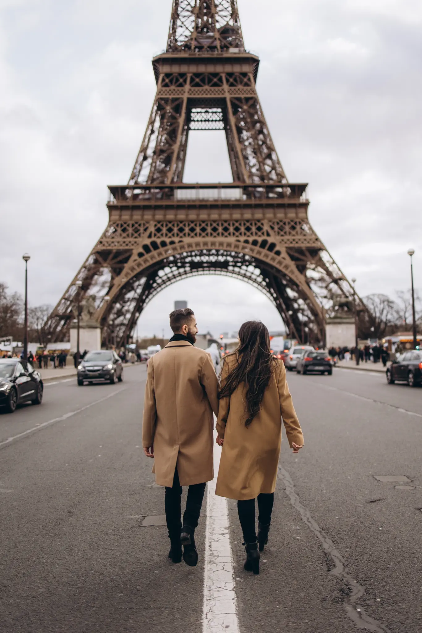 Couple standing in the middle of the road below the Eiffel Tower at Pont d’Iéna