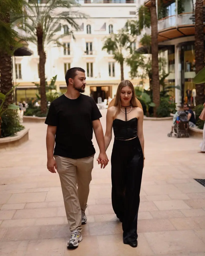 Couple walking hand in hand through a palm-lined square in Monte-Carlo