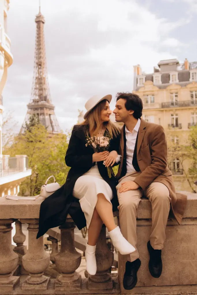 Couple on a stone balustrade with the Eiffel Tower and Haussmann buildings