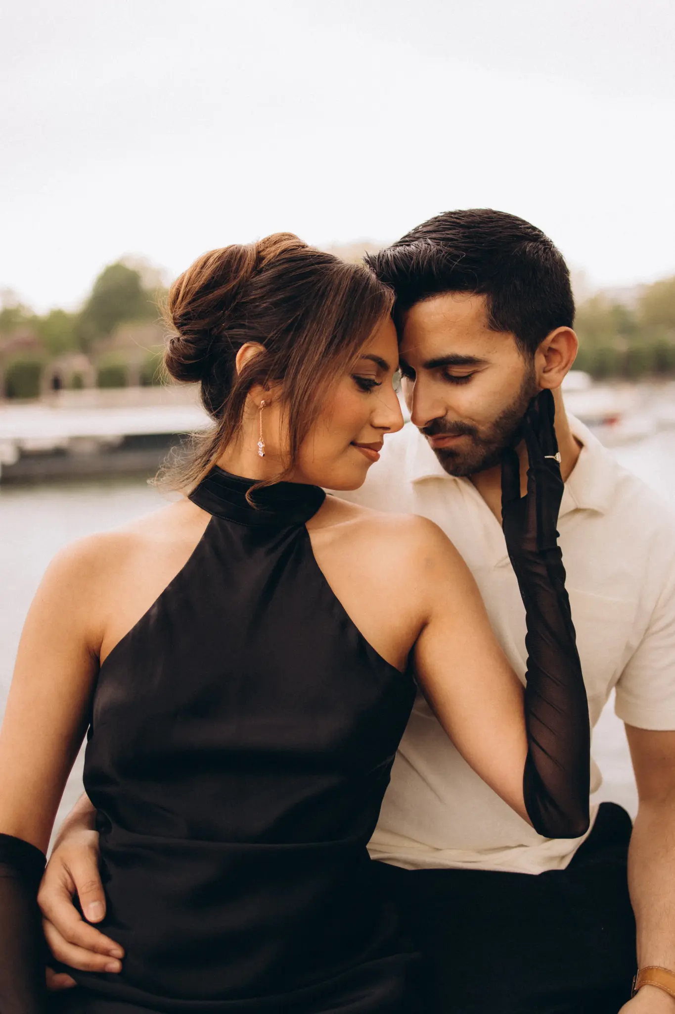 Couple in black evening outfits close together by the Seine in Paris