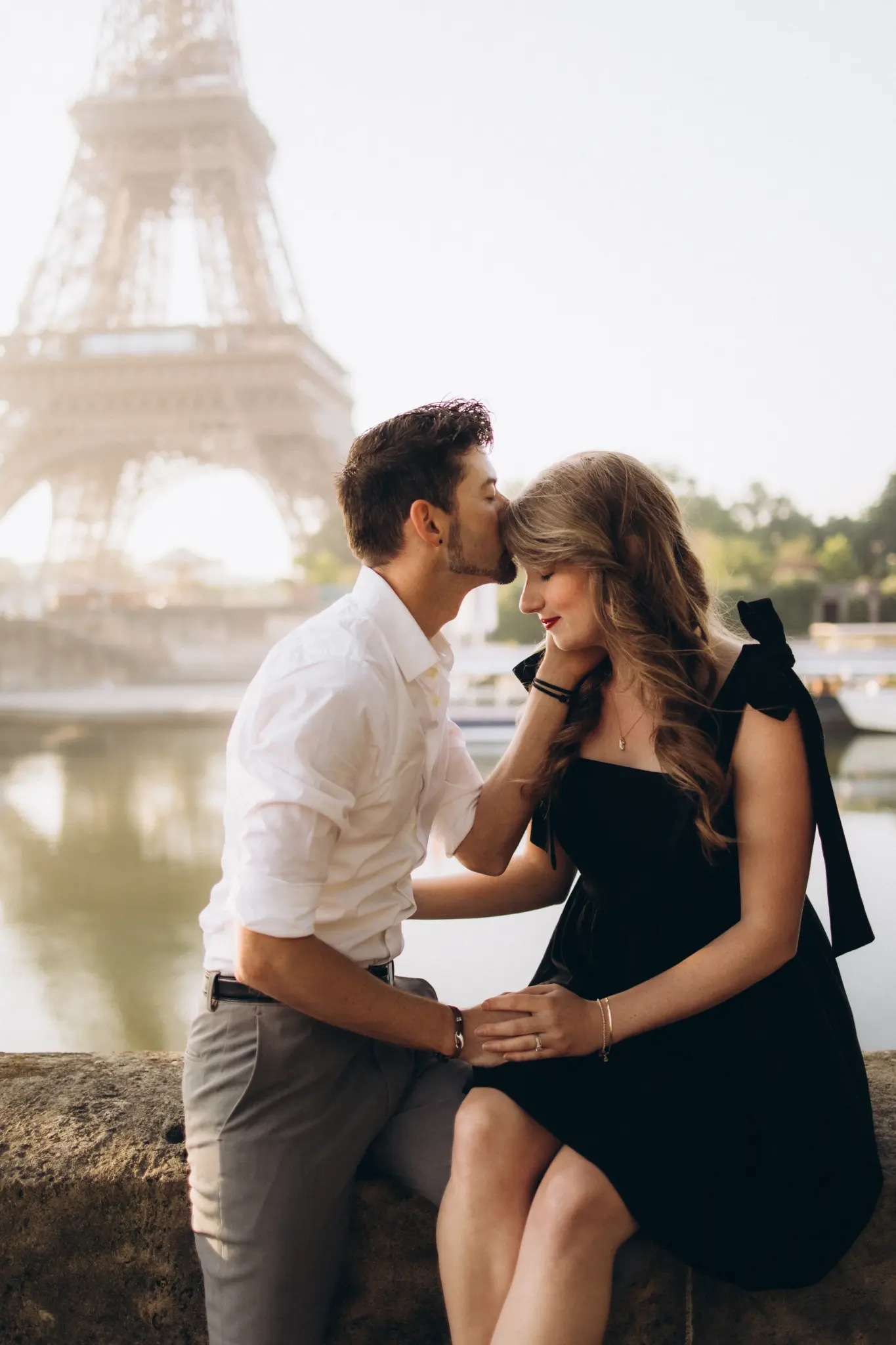 Woman in a black dress sitting on a Paris balustrade beside her partner