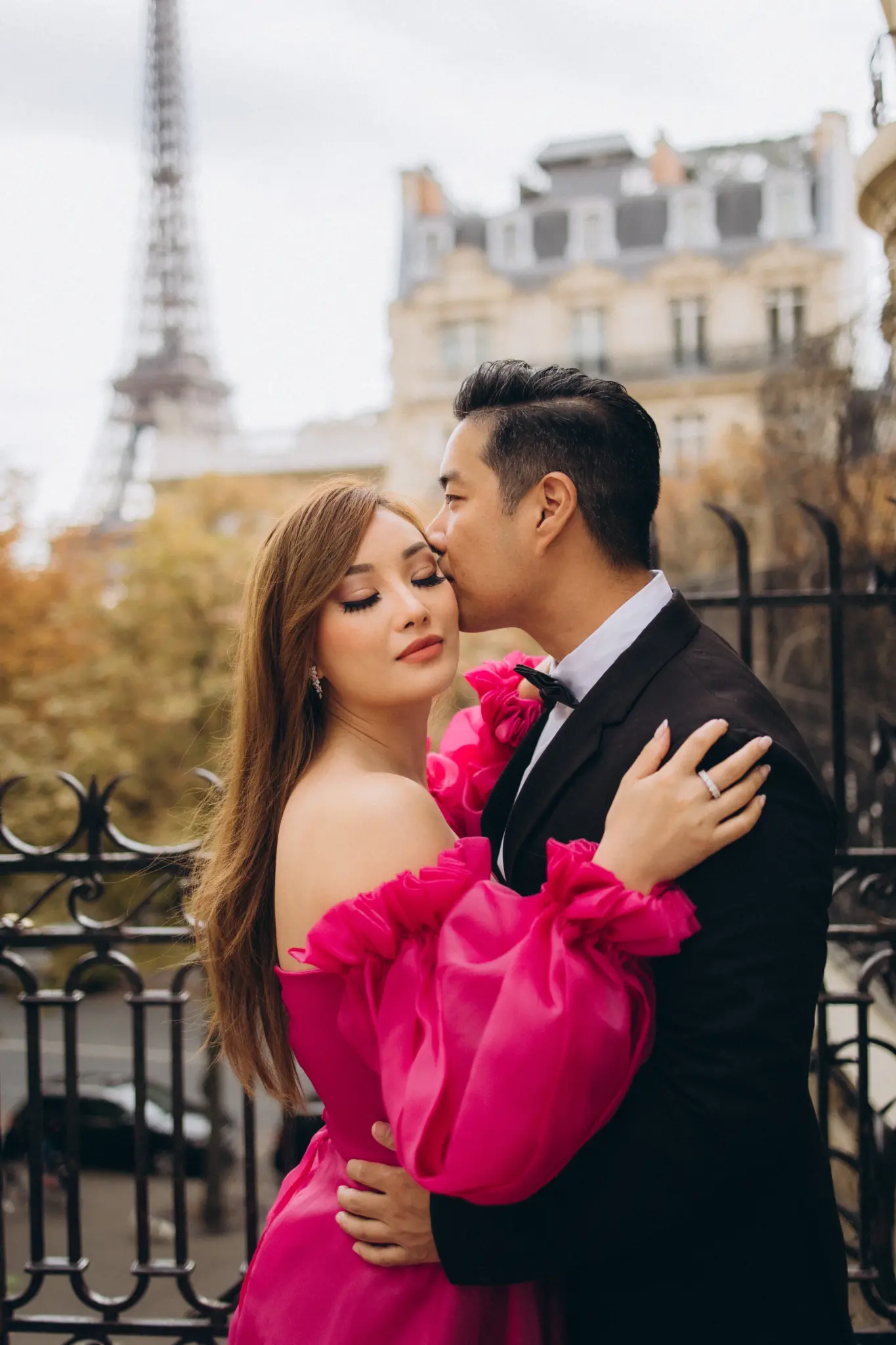 Couple kissing at the iron gate of Avenue de Camoëns, the woman in a pink dress, Eiffel Tower behind