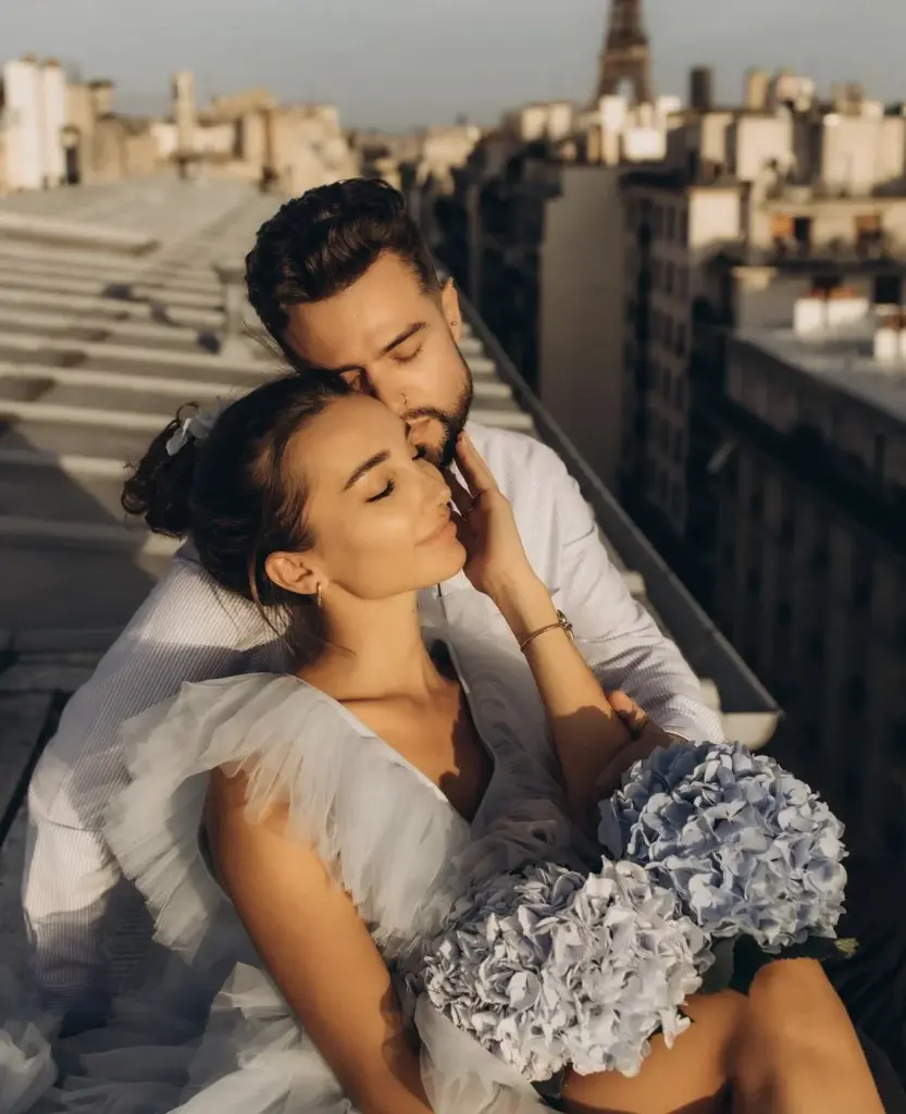 Woman in a gown reclining with her partner on a Paris rooftop