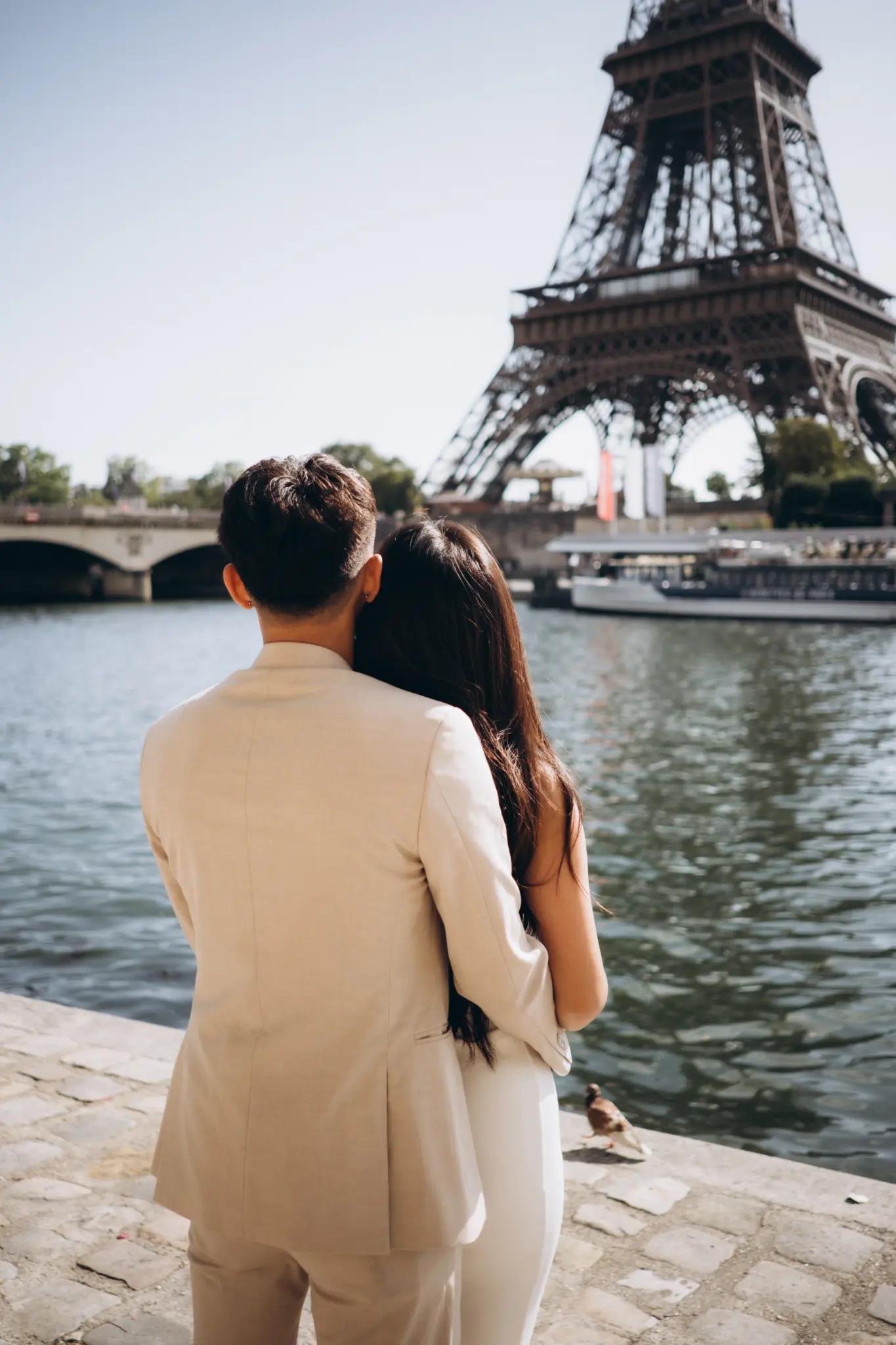Couple seen from behind by the Seine with the Eiffel Tower