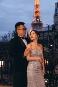 Couple in evening wear, the woman in a sequin dress, at night near the Eiffel Tower