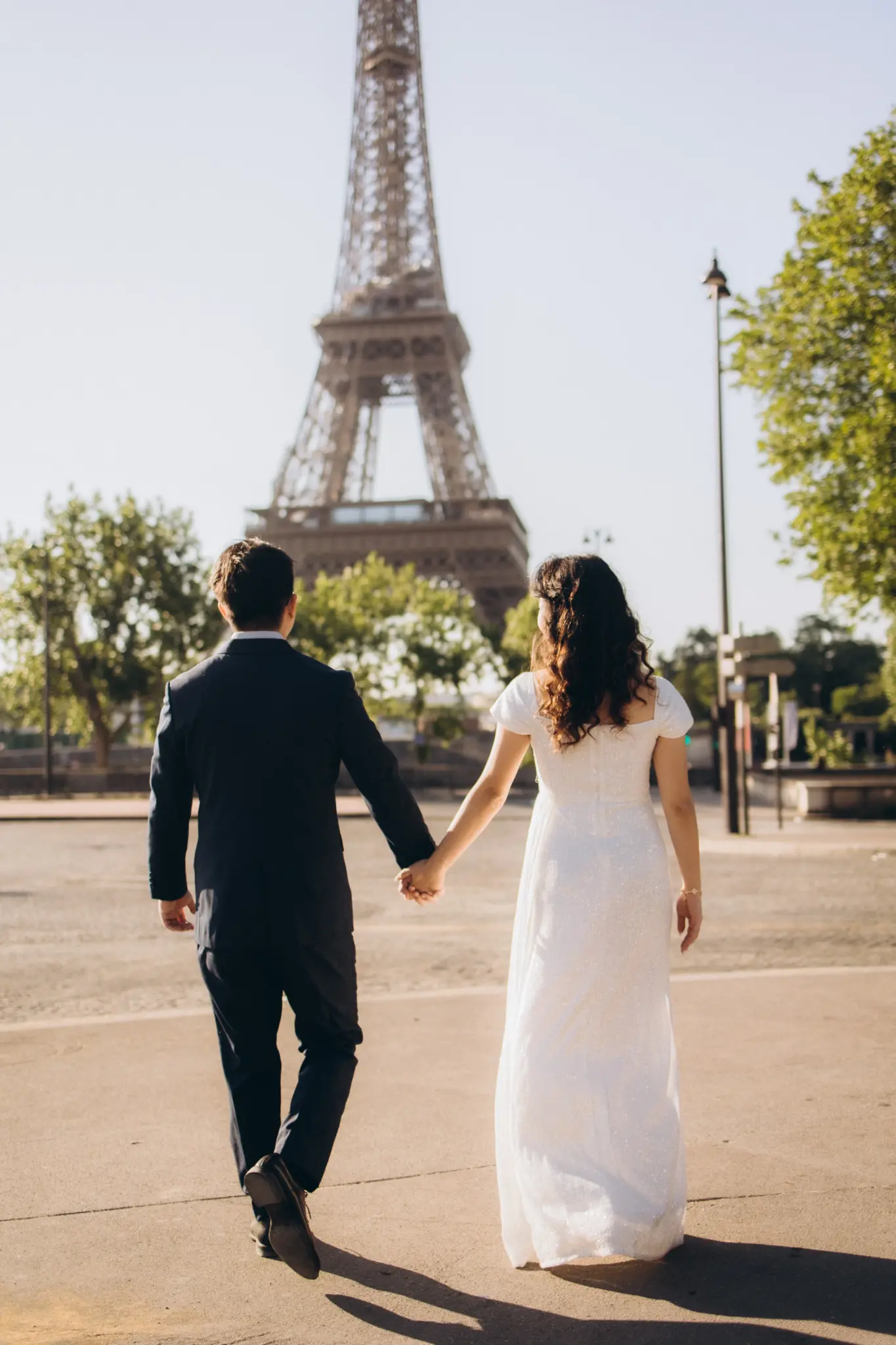 Couple walking hand in hand towards the Eiffel Tower
