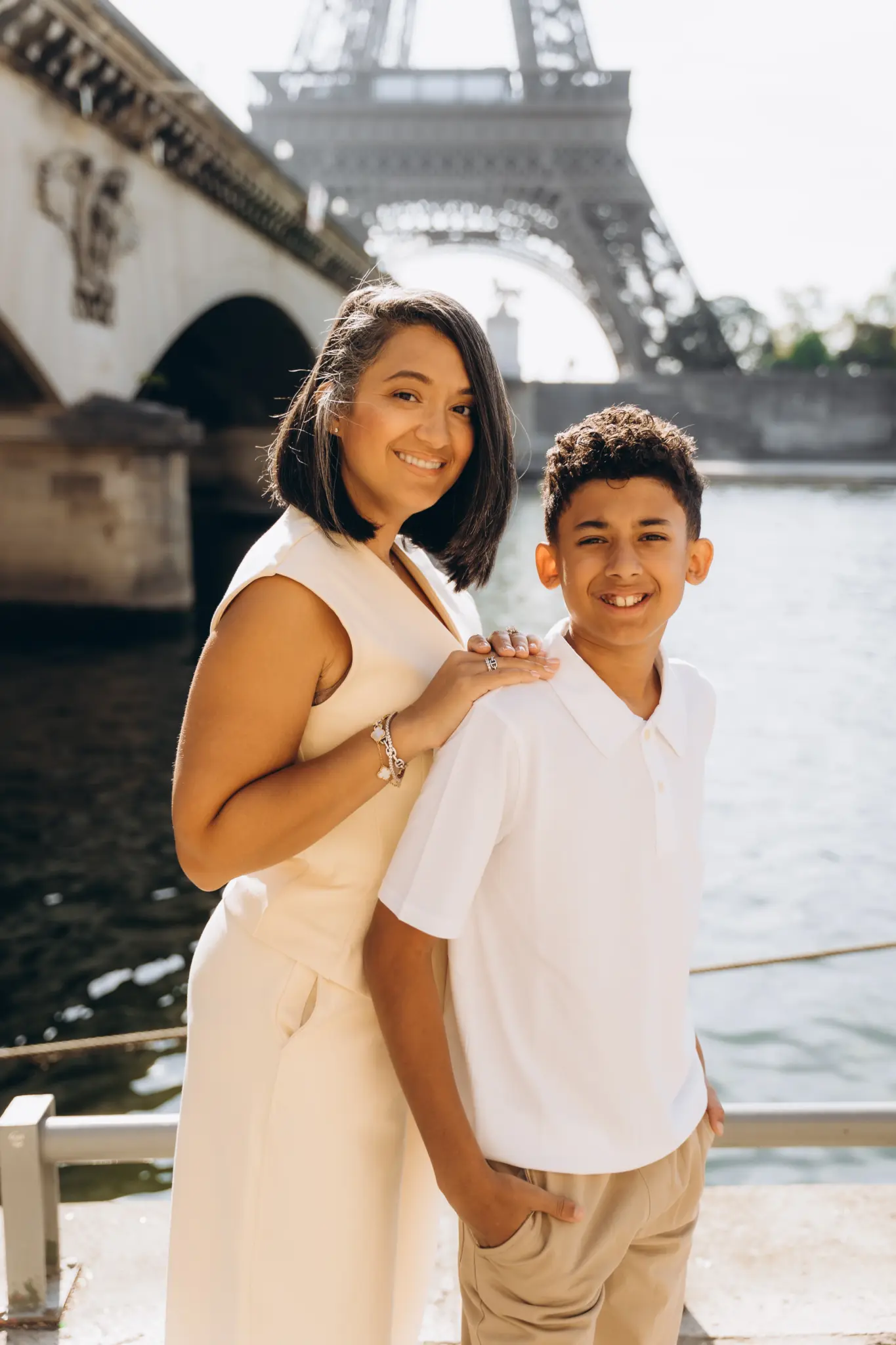 Mother and teenage son smiling by the Seine with Pont d’Iéna and the Eiffel Tower behind