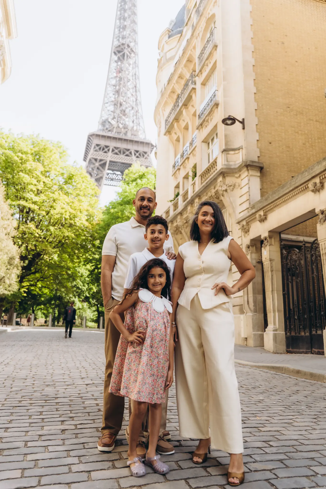 Family of four on a cobbled Paris street between Haussmann buildings and the Eiffel Tower