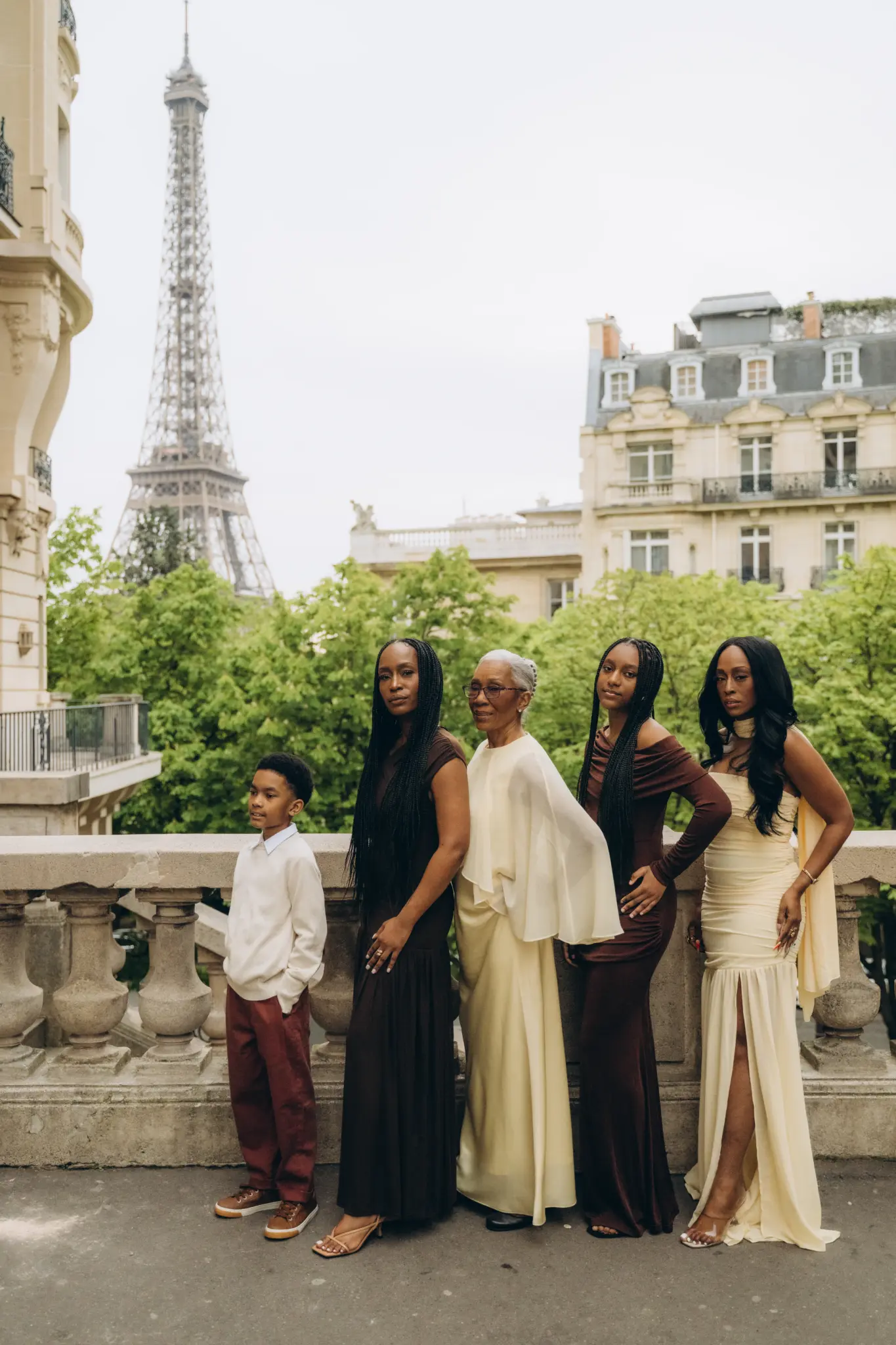 Family of five in elegant dresses by a stone balustrade with the Eiffel Tower
