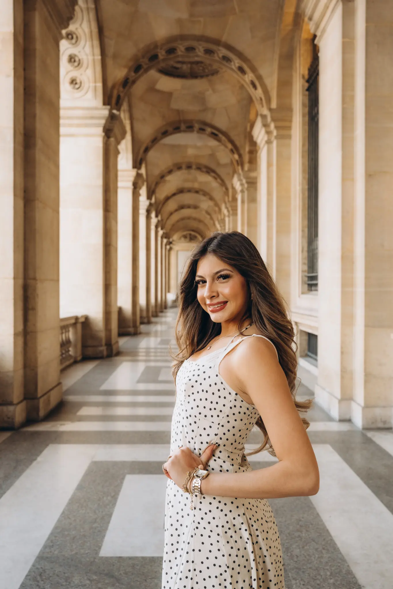 Woman in a polka-dot dress in the stone arcades of the Louvre