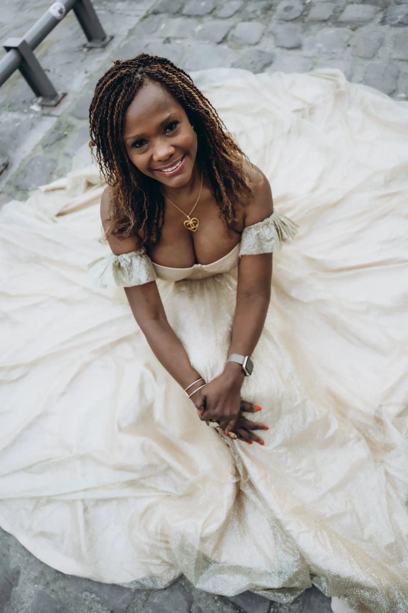 Woman in an ivory ball gown seen from above, the skirt spread on the cobblestones