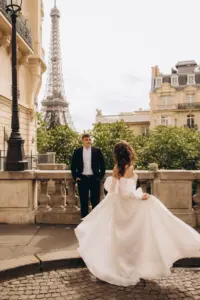 Bride swirling her wedding dress on a cobbled terrace, groom watching, Eiffel Tower in the distance