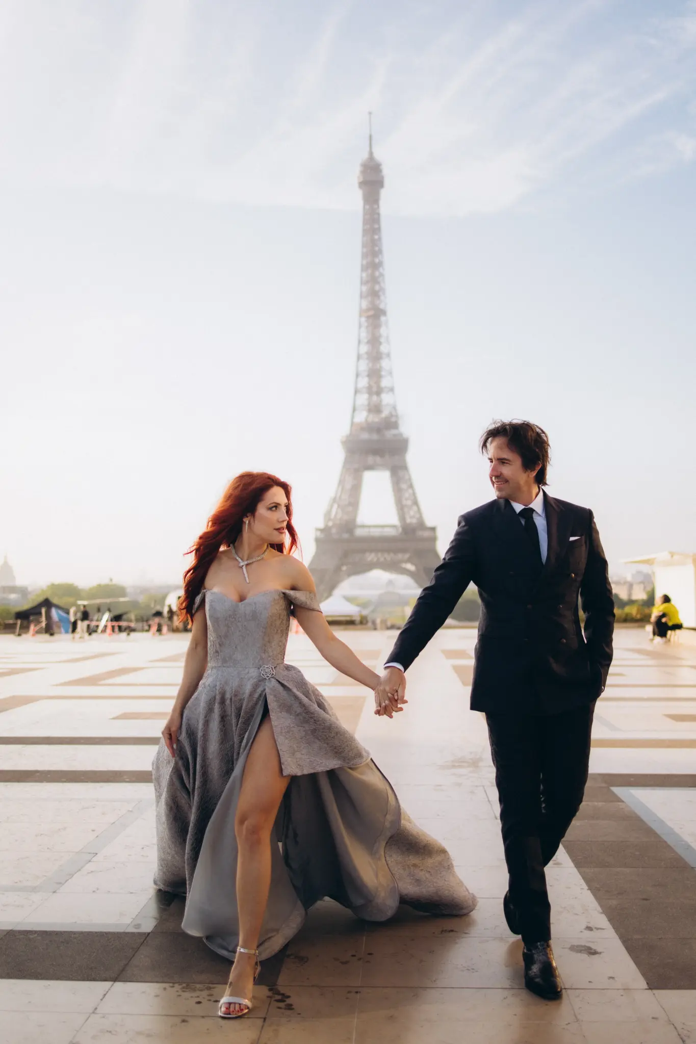 Couple walking hand in hand across Trocadéro, silver gown and dark suit, Eiffel Tower ahead