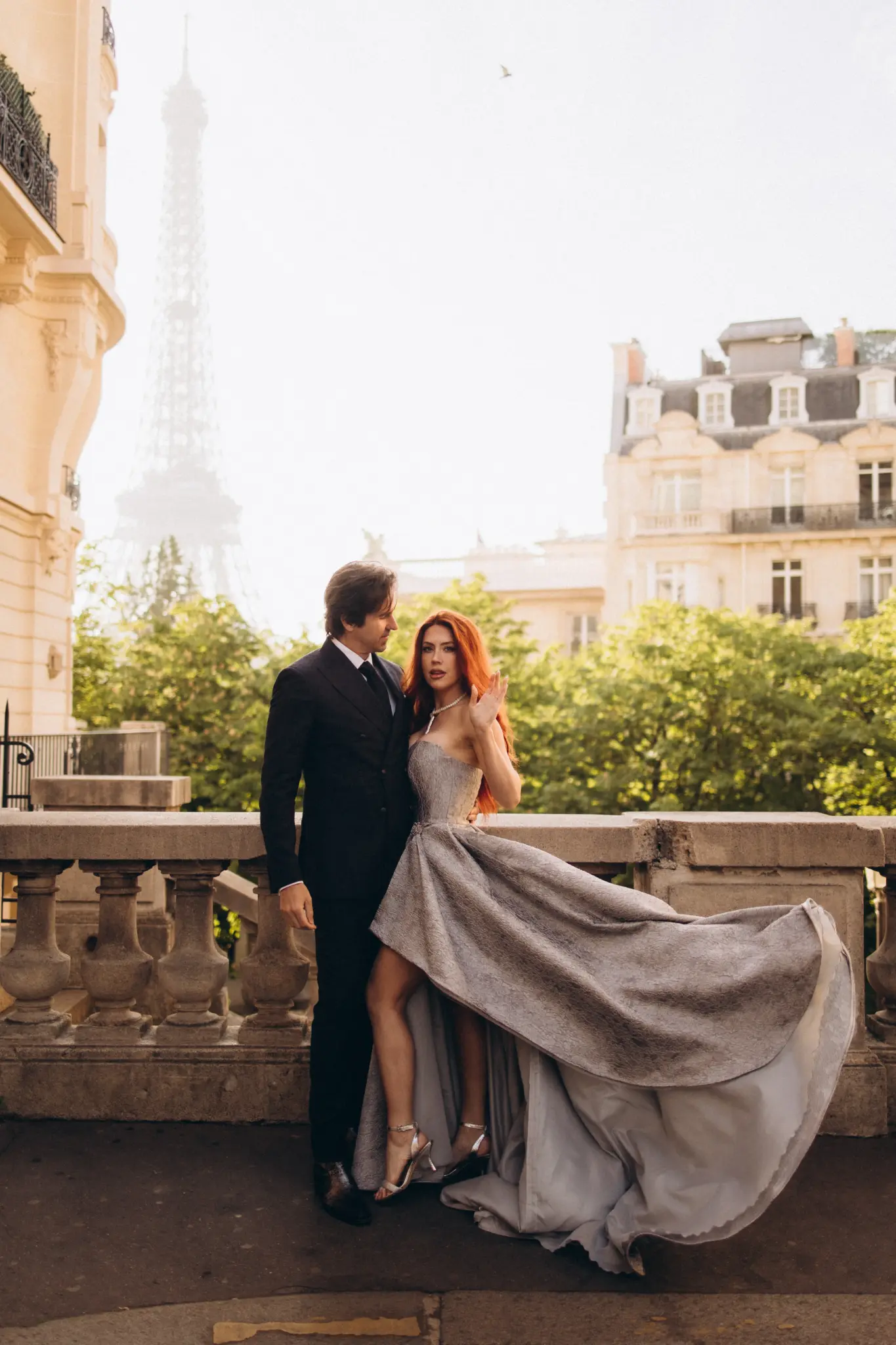 Silver gown flying by a stone balustrade, couple with the Eiffel Tower behind
