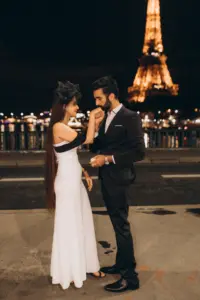 Engaged couple at night in front of the lit Eiffel Tower