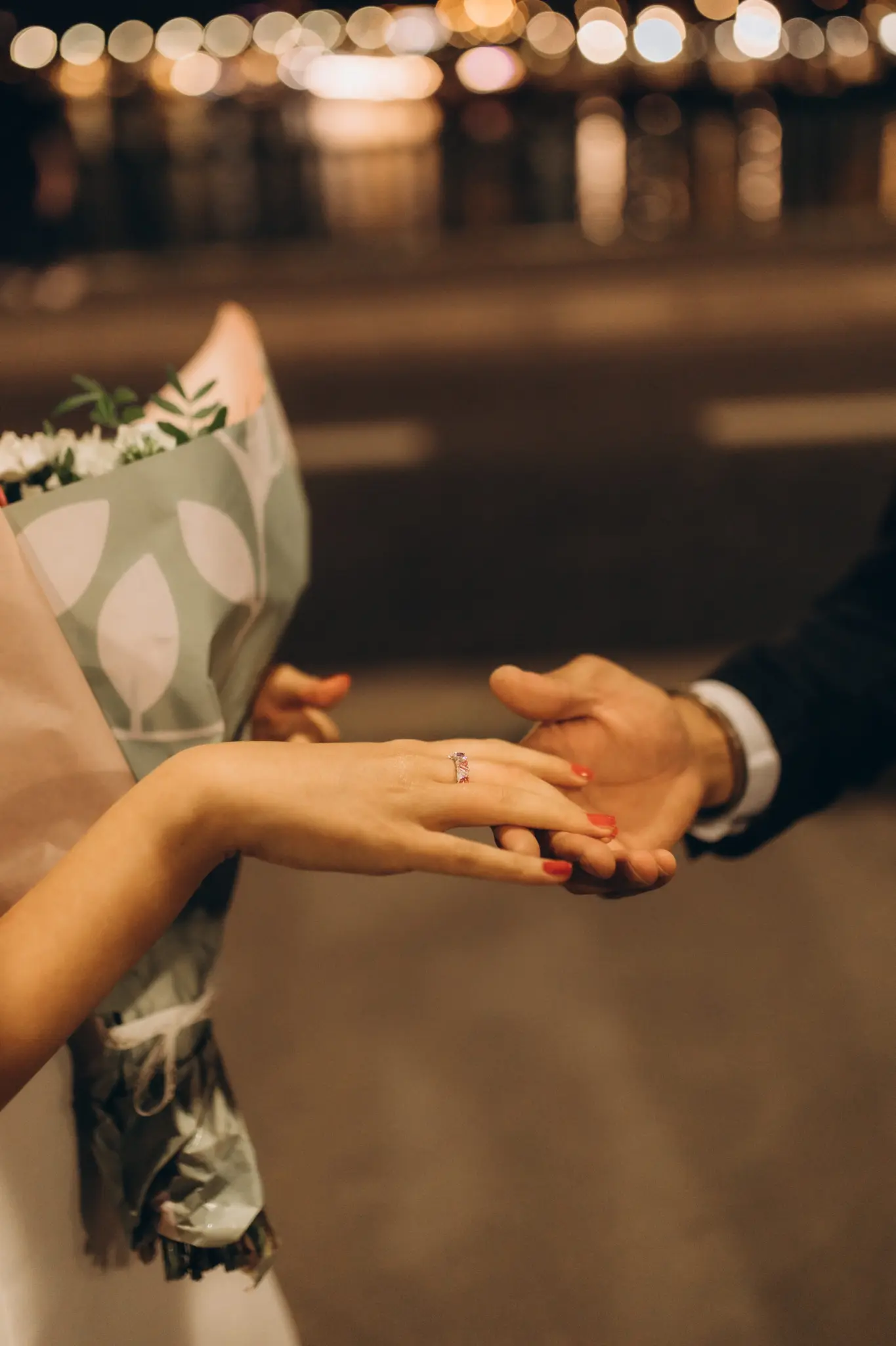 Hands with an engagement ring at night after a Paris proposal
