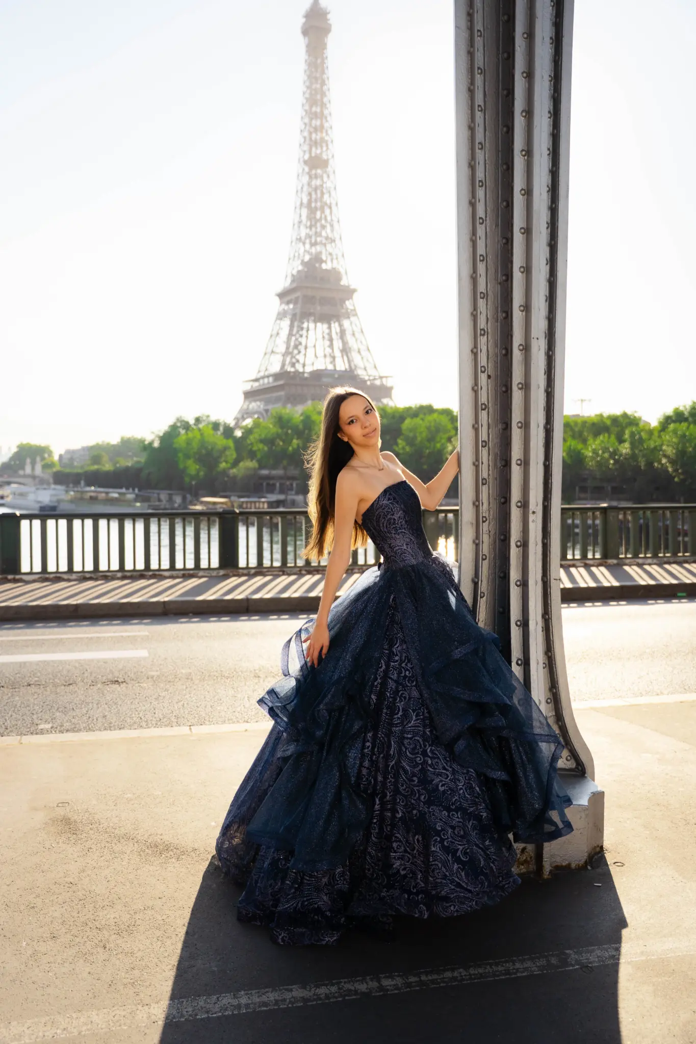 Quinceañera in a navy ball gown by a column of Pont de Bir-Hakeim, Eiffel Tower behind