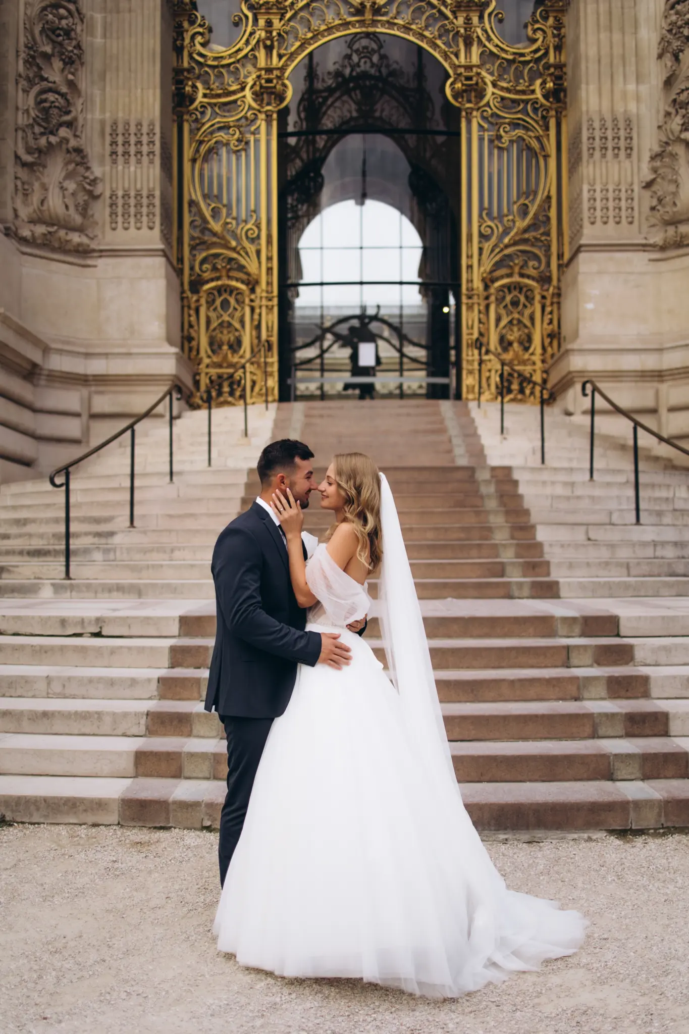 Bride and groom kissing on the steps of the Petit Palais under its gilded gate