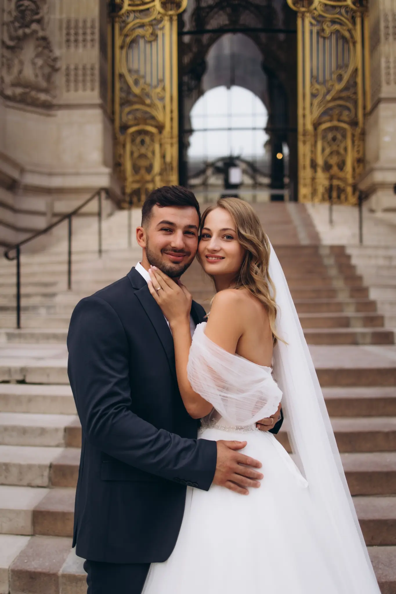 Groom holding the bride on the Petit Palais staircase, both smiling at the camera