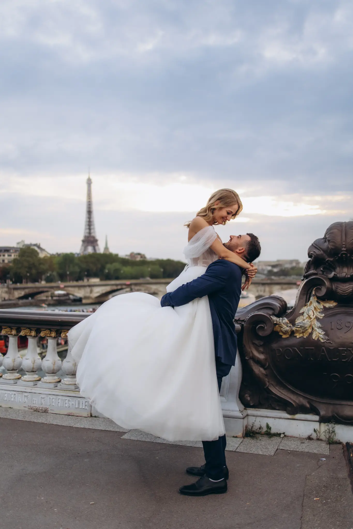 Groom lifting the bride on Pont Alexandre III, Eiffel Tower on the horizon